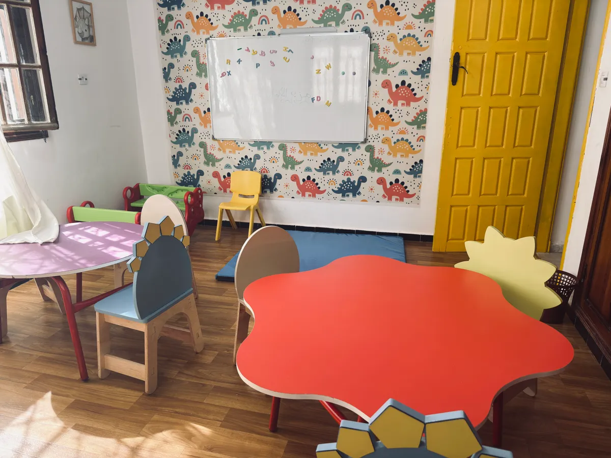 Table en forme de fleur, tableau blanc et papier peint à motifs de dinosaures.