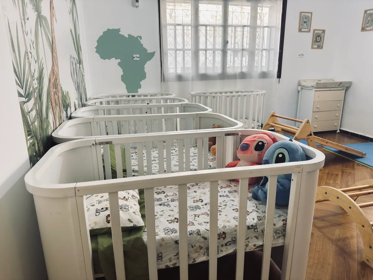 Pièce calme avec lits à barreaux blancs, peluches et carte de l’Afrique au mur.