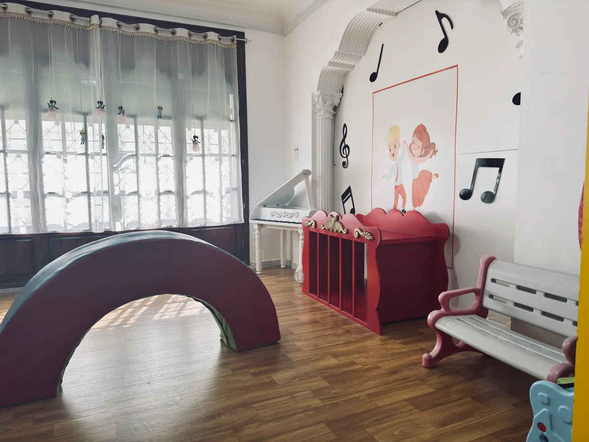 Grande arche à bascule, banc blanc et décor musical dans une pièce baignée de lumière.