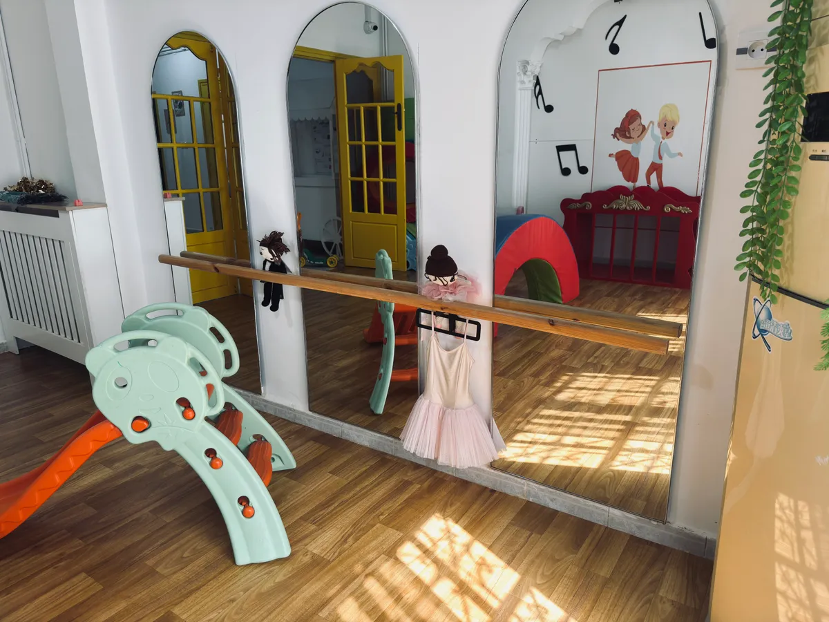 Mur de miroirs en arches avec barre d’appui en bois, toboggan et tapis.
